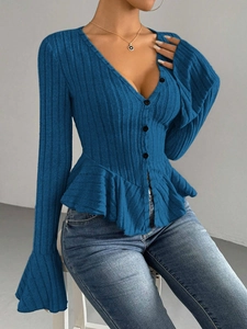 Detail of blue long-sleeve knit top featuring a V-neck and elegant ruffled peplum hem
