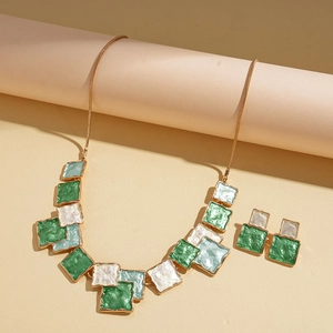 Close-up of geometric square necklace and earrings set in green and white enamel