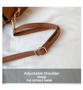 Détail de la bandoulière réglable en cuir marron avec des boucles dorées et des coutures
