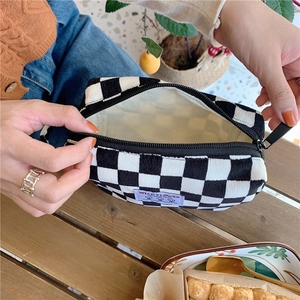Détail d'une trousse de toilette en velours à carreaux avec écusson et fermeture éclair noire