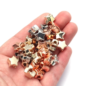 Close-up of gold, silver, and rose gold star-shaped metallic loose beads held in hand