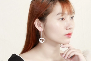 Close-up of heart-shaped pearl drop earrings on model in minimalist silver style