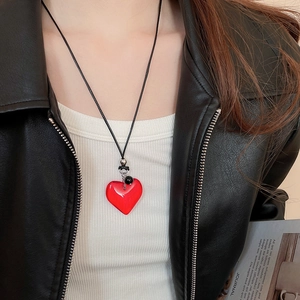 Detail of red heart pendant with black woven cord worn on model with leather jacket