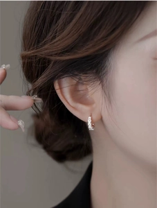 Detailed view of silver daisy hoop earring with intricate petal texture on a female model