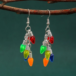 Gros plan de boucles d'oreilles ampoules de Noël colorées sur une branche et fond vert