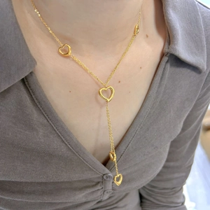 Gold titanium steel long necklace with multiple hollow heart pendants on a model