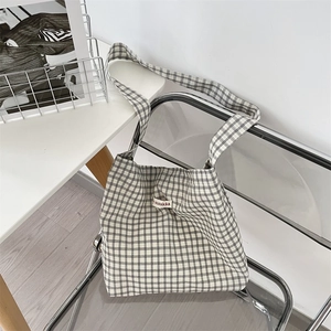 Close-up of minimalist black and white checkered canvas tote bag with woven logo label