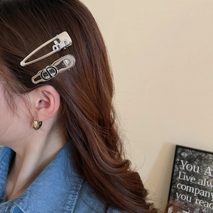 Detail view of silver Y2K hair clips featuring luxury brand style logo engravings