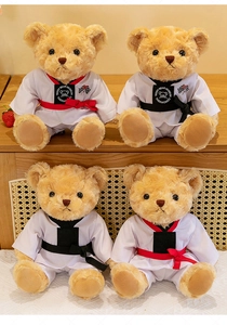 Ours en peluche en uniformes de taekwondo avec ceintures rouges et noires, fond en bois.