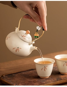 Pouring tea from a ceramic teapot with a metal handle and elegant orchid flower motifs