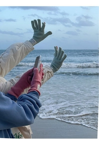 Outdoor detail of long knitted wool gloves in pale green and pink with winter labels