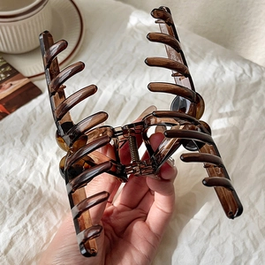 Detail shot of large amber acrylic hair claw clip with strong metal spring and teeth