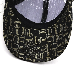 Close-up of baseball cap brim featuring vintage gold monogram pattern on black twill fabric
