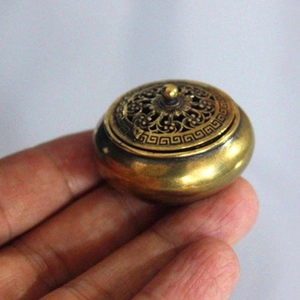Macro di un mini bruciatore di incenso in ottone antico tenuto tra le dita