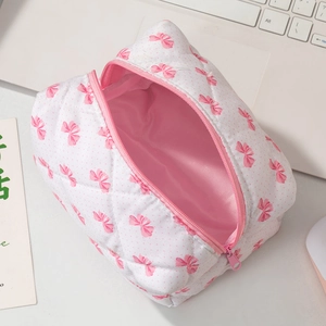 Trousse à cosmétiques matelassée à nœuds roses avec fermeture éclair sur un bureau