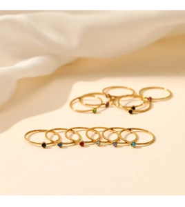Macro detail of minimalist gold stackable rings with vibrant round birthstones set on silk
