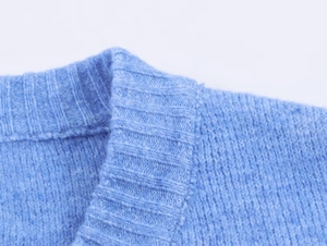 Dettaglio del colletto a costine e della morbida trama in maglia del maglione blu