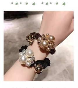 Close-up of pearl hair ties with crystals and gold beads on elastic pleated fabric