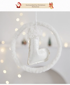Dettaglio di una ghirlanda di peluche bianca con stivale natalizio glitterato su sfondo bokeh
