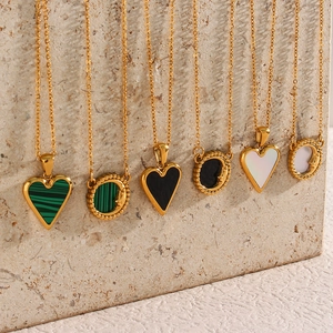 Golden heart and moon shell pendant necklaces displayed on beige marble background