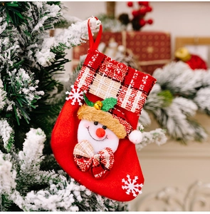 Gros plan d'une chaussette de Noël en peluche rouge avec bonhomme de neige et cloches