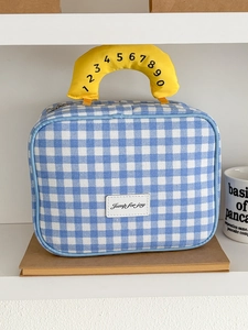 Details der blau-weiß karierten Kulturtasche mit gelbem Griff und Logo-Etikett