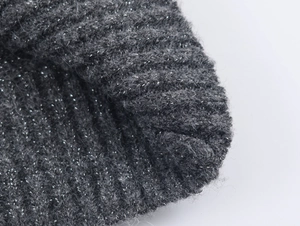 Macro detail of dark grey knit cardigan fabric with sparkling silver metallic thread texture