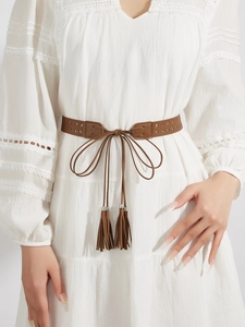 Detail of brown faux suede waist belt featuring hollow cutouts and fringe with metal beads