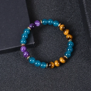 Close-up of tiger eye and blue crystal beaded bracelet with gold spacer beads on black