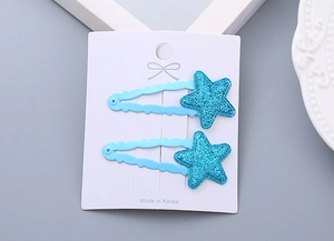 Close-up of two blue glitter star hair clips on a white display card for girls