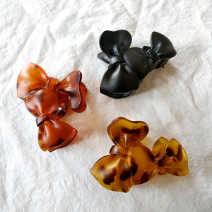 Close-up of three bow-shaped hair claws in black, amber, and tortoiseshell patterns