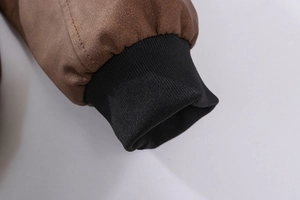 Detailaufnahme des braunen Lederjackenärmels mit schwarzen Rippstrickbündchen und Nähten