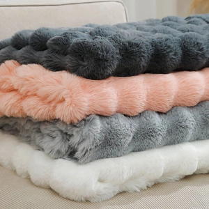 Close-up of thick faux rabbit fur blankets in dark grey, pink, light grey, and white