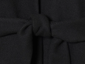 Close-up of the elegant black wool coat featuring a detailed waist tie-knot design