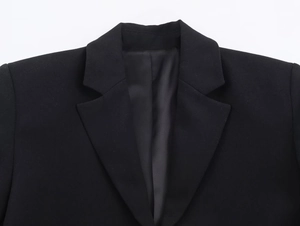 Detailed close-up of the elegant notched lapel and collar on a black blazer dress