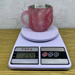 Pink mineral crystal coffee mug with stainless steel liner weighing 254g on a scale
