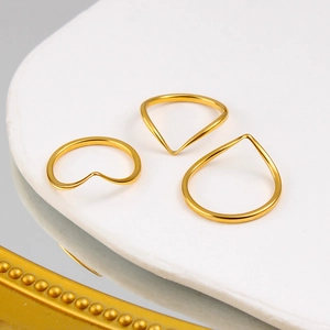 Detailed view of three minimalist gold-plated V-shaped and heart rings on a tray