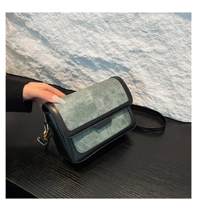 Detail of grey-green and black crossbody bag with suede and leather texture finish