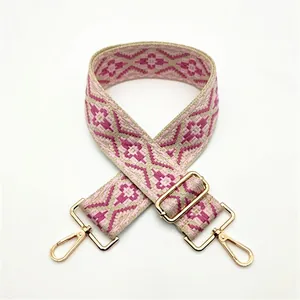 Detail of pink and beige geometric woven shoulder strap with gold metal buckles