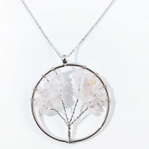 Detailed close-up of handmade Tree of Life pendant with pink crystal and silver wire