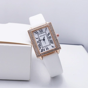 Close-up of rectangular rose gold watch with rhinestone bezel and white leather strap