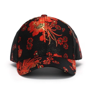 Macro detail of red and gold phoenix floral embroidery on a black cotton baseball cap