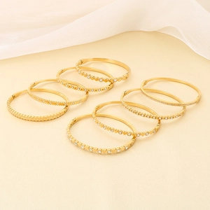 Dettaglio di vari bracciali rigidi in acciaio inossidabile dorato con strass chiari