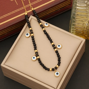 Gold evil eye necklace with black faceted beads on display box with vintage background