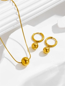 Detail of gold beaded necklace and matching hoop earrings on white geometric prop