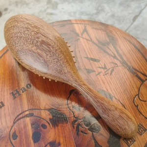 Sandalwood massage hairbrush on decorative wooden base with panda and bamboo patterns