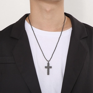 Detail of male model wearing a grey punk cross necklace with woven grid texture