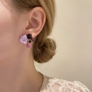 Floral cat-eye stone earrings in purple tones worn by a model for a sweet vintage look