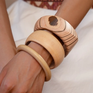 Detail of three vintage stackable wood bangles with natural grain on female wrist