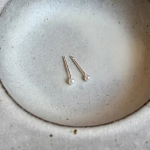Close-up of minimalist freshwater pearl studs with S925 sterling silver pins